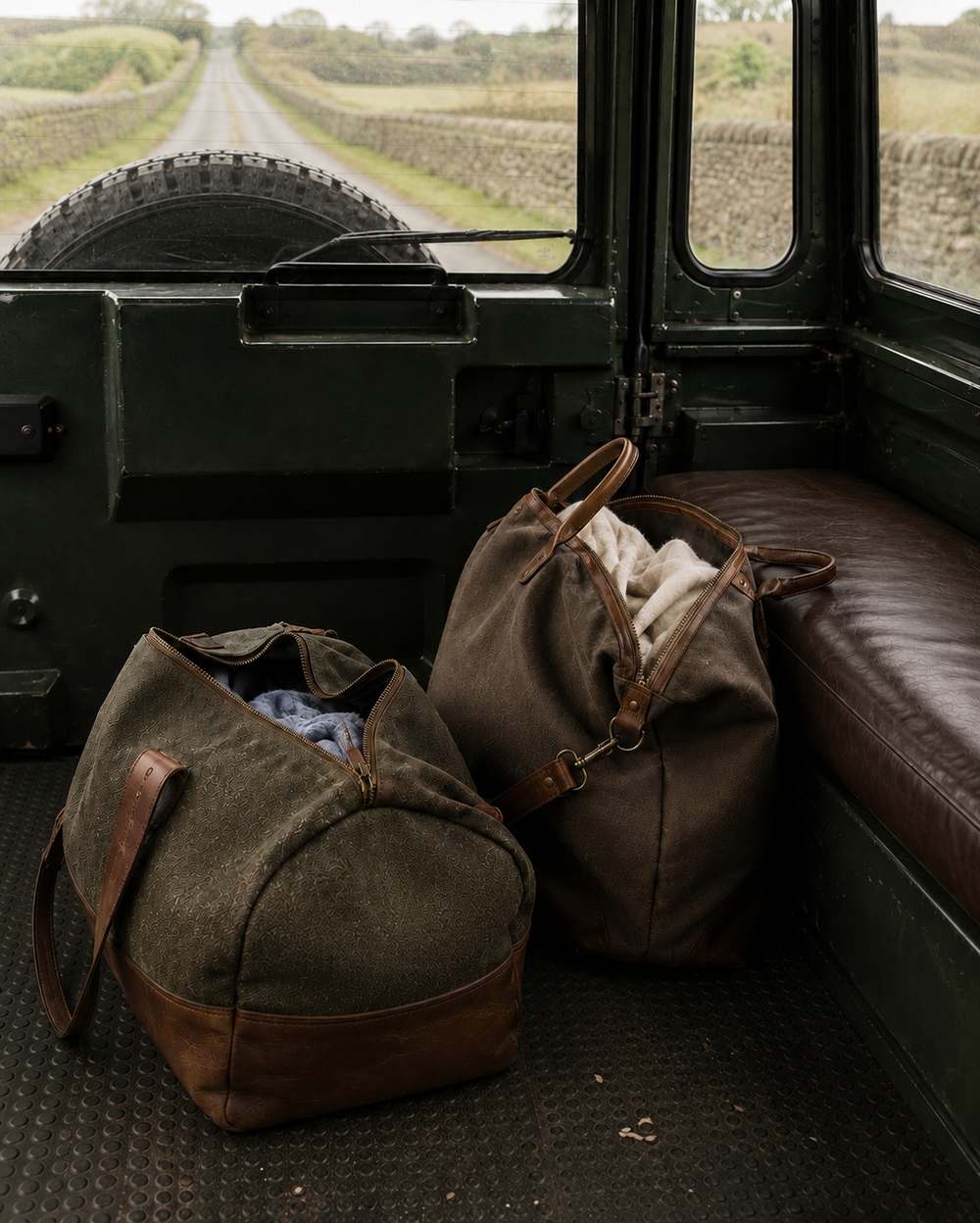 Two weekend bags in the back of a Land Rover on a country lane